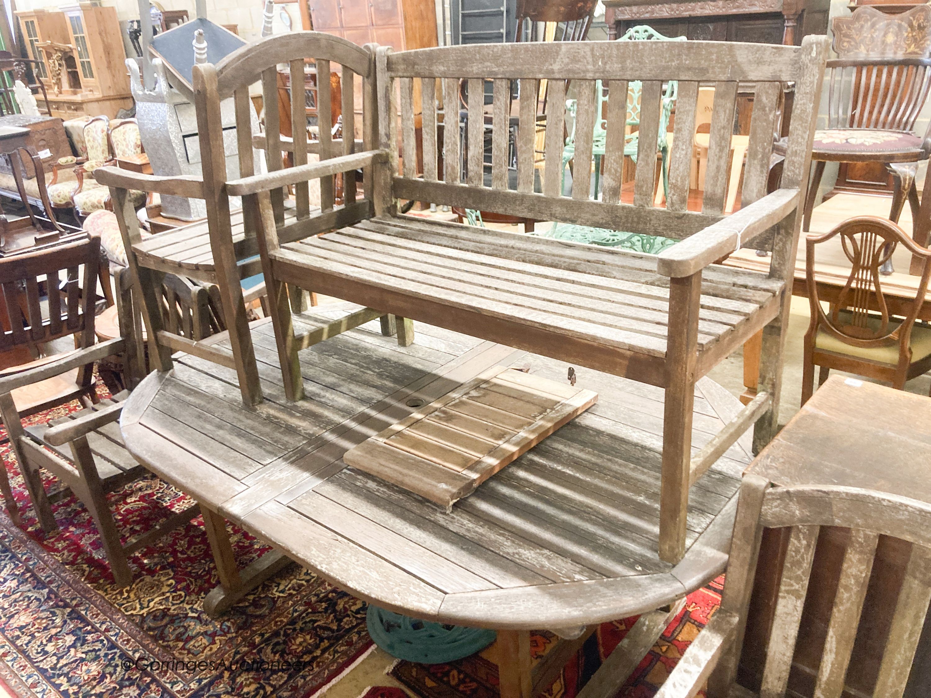 A weathered teak extending garden table, length 190cm, depth 120cm, height 74cm a bench and four weathered teak armchairs